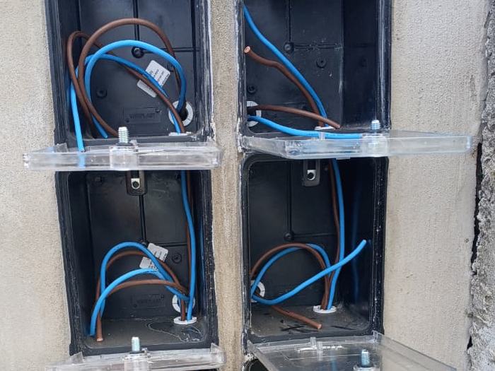 Pilar con seis cajas de medidor empotradas y abiertas, con los conductores de fase y neutro ya pasados, listas para la colocación de los medidores.