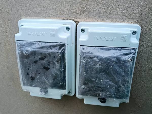 Dos cajas de medidor plásticas empotradas en el pilar, todavía con el film de obra, listas para que la distribuidora coloque los equipos.